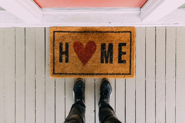 someone looking down at a welcome mat with home written on it