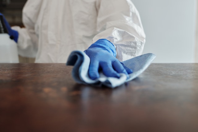 someone cleaning a surface with a rag and gloves