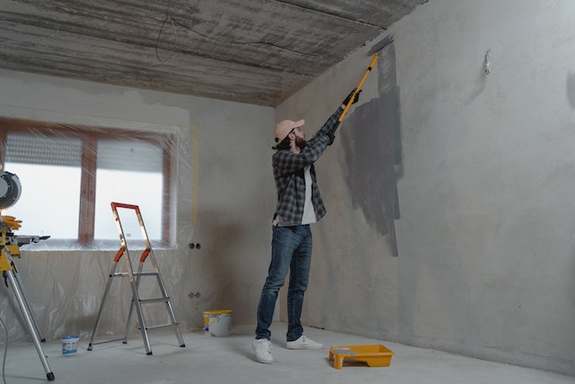 Person painting a wall with gray paint