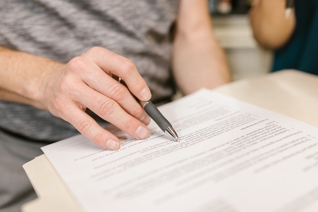 Hand holding a pen and reviewing a printed document