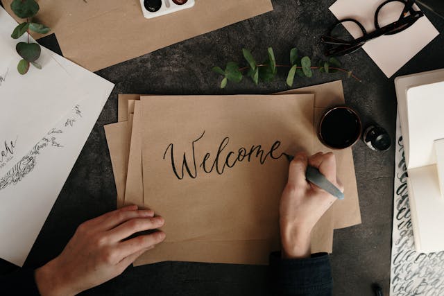 person-writing-the-word-welcome-on-kraft-paper
