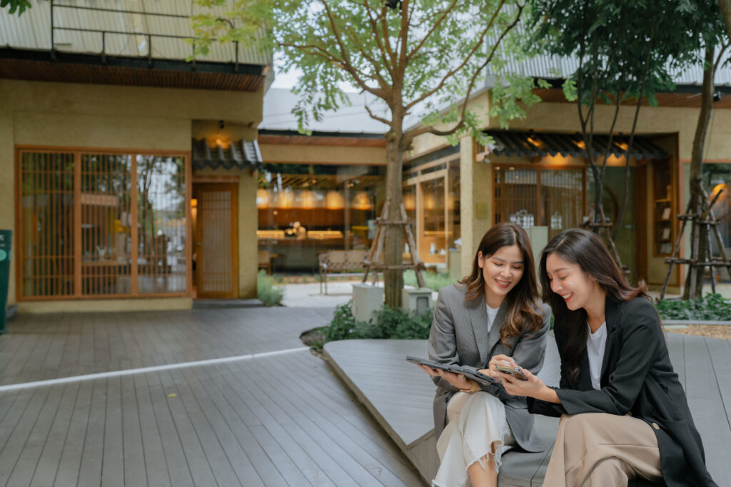 two-people-sitting-on-bench-looking-at-a-phone-and-tablet