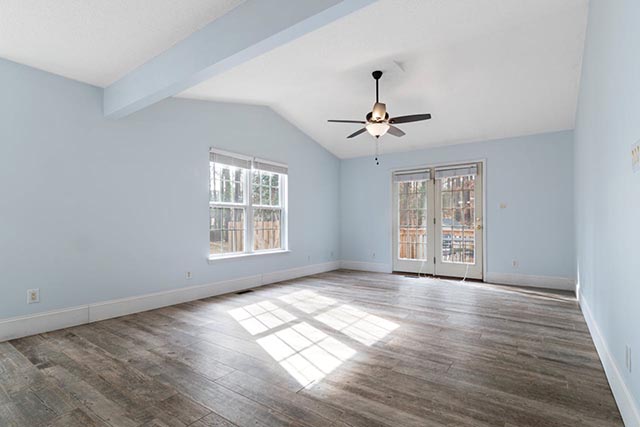 empty-room-with-light-blue-walls-wood-look-flooring-a-ceiling-fan-and-large-windows
