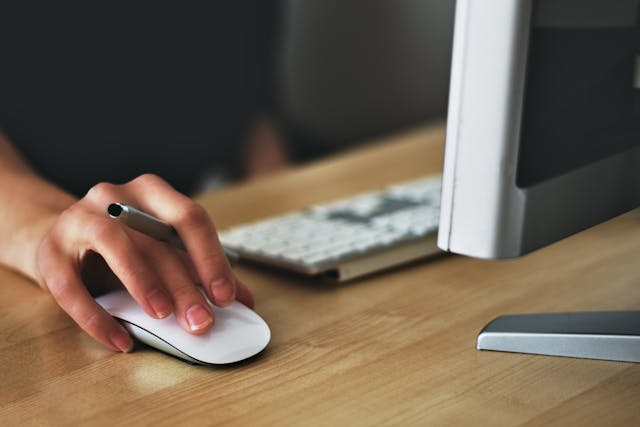 hand-on-computer-mouse-on-wood-desk
