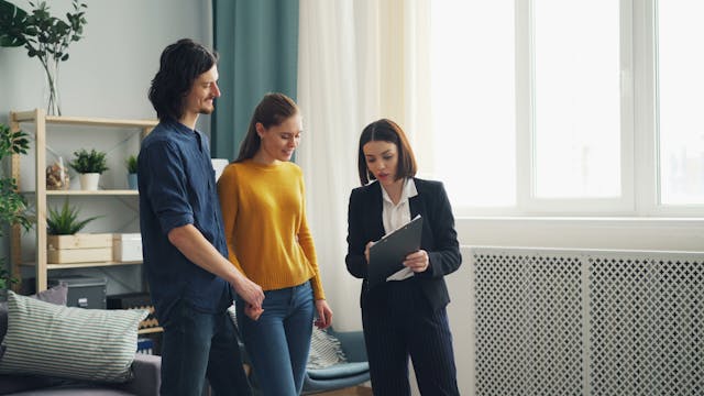 three-people-looking-at-clipboard-discussing-business