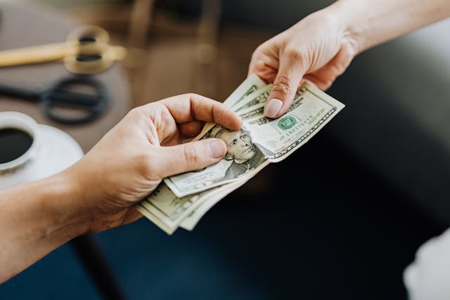 a hand passing money to another